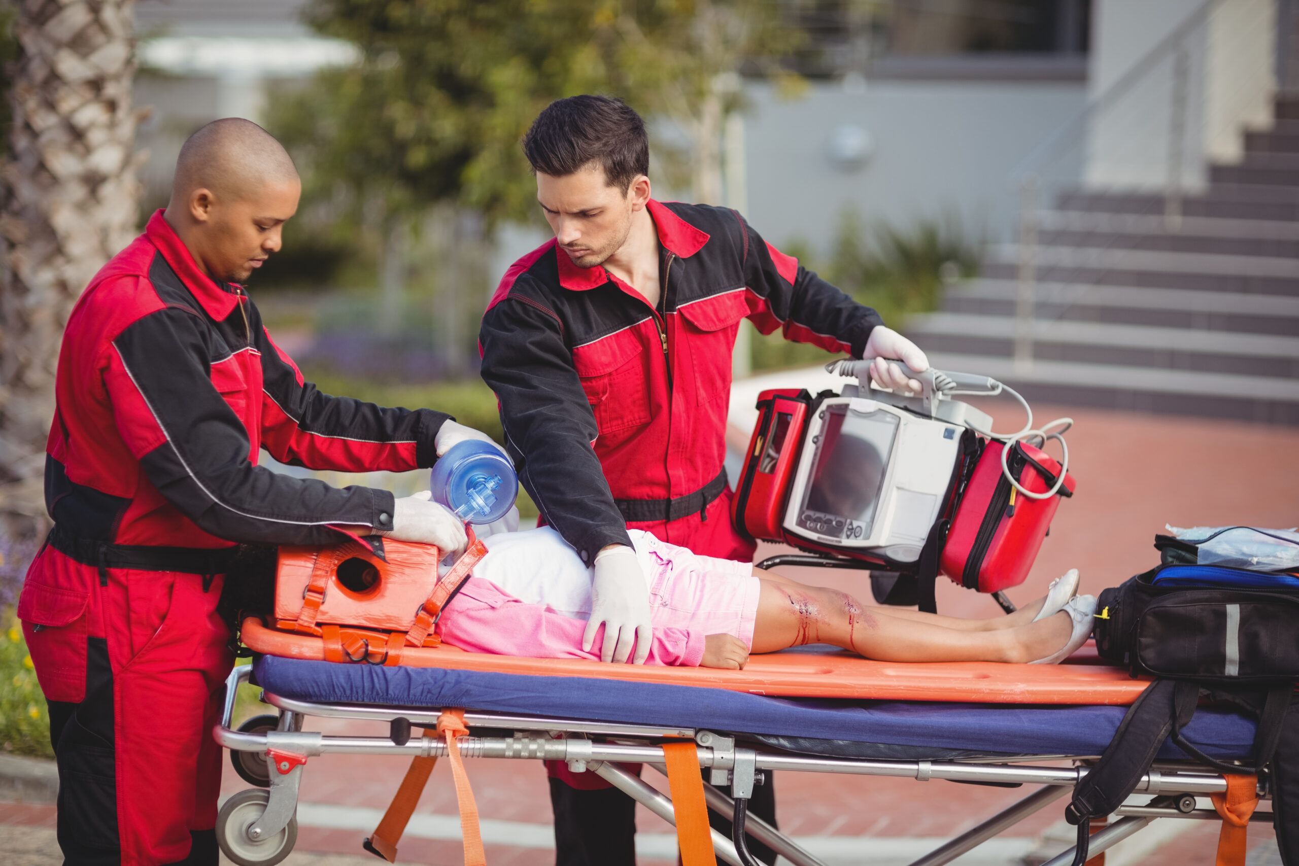 Paramedic giving oxygen to injured girl at accident spot